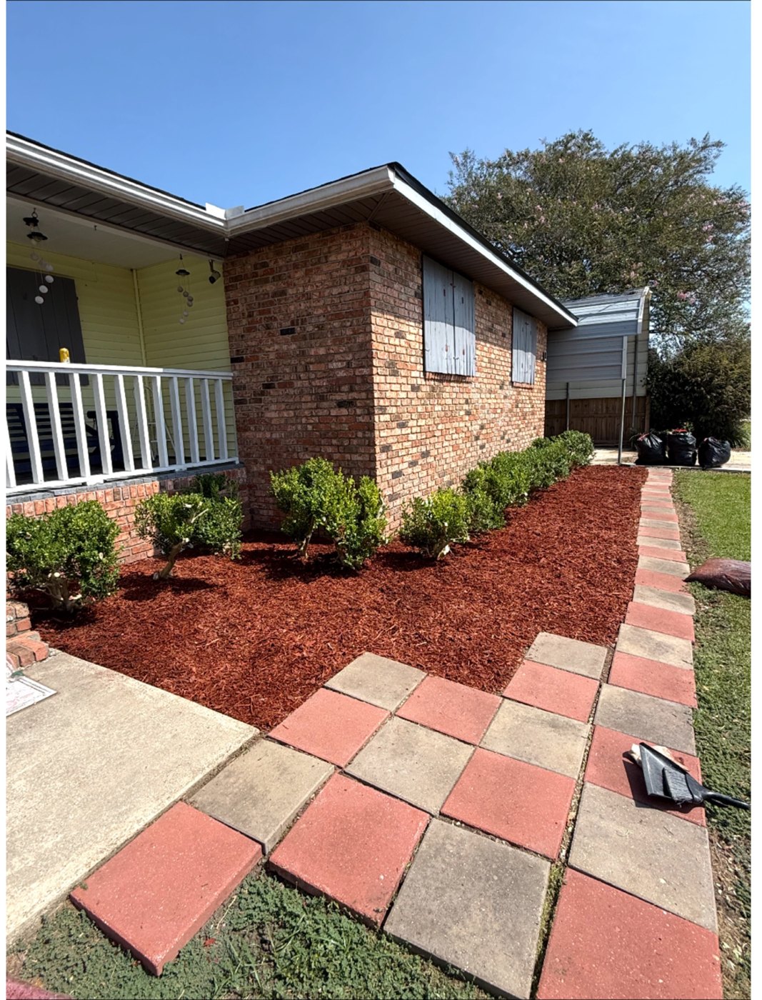 Freshly mulched flowerbed with neatly trimmed hedges along a brick home