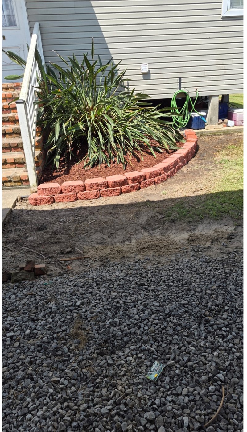After: the same flowerbed with a neat curved brick border, trimmed plant, and fresh mulch